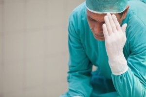 15551482 - concerned surgeon sitting in the hospital with hand on head