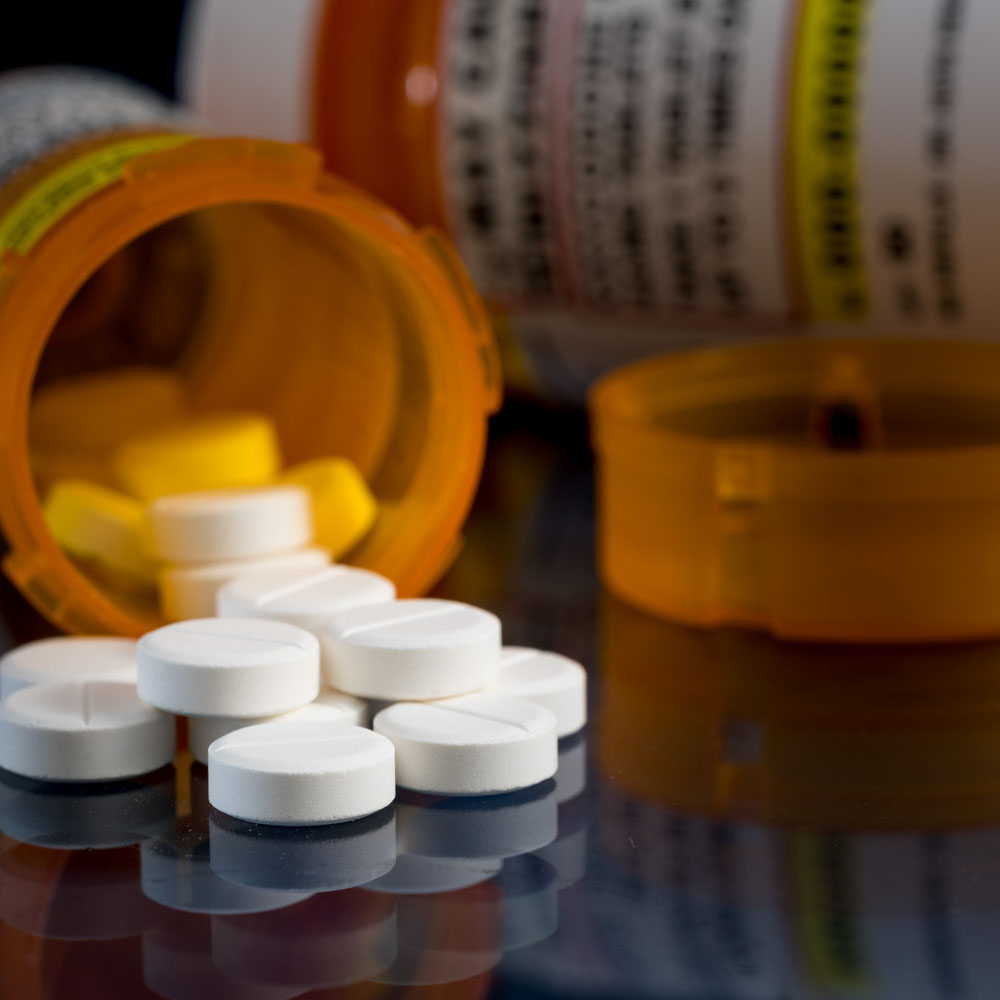 Open bottles of Oxycodone with pills spilled on a table, symbolizing addiction as a result of unresolved trauma or PTSD treated at Deer Hollow's addiction rehabilitation center for first responders and veterans.