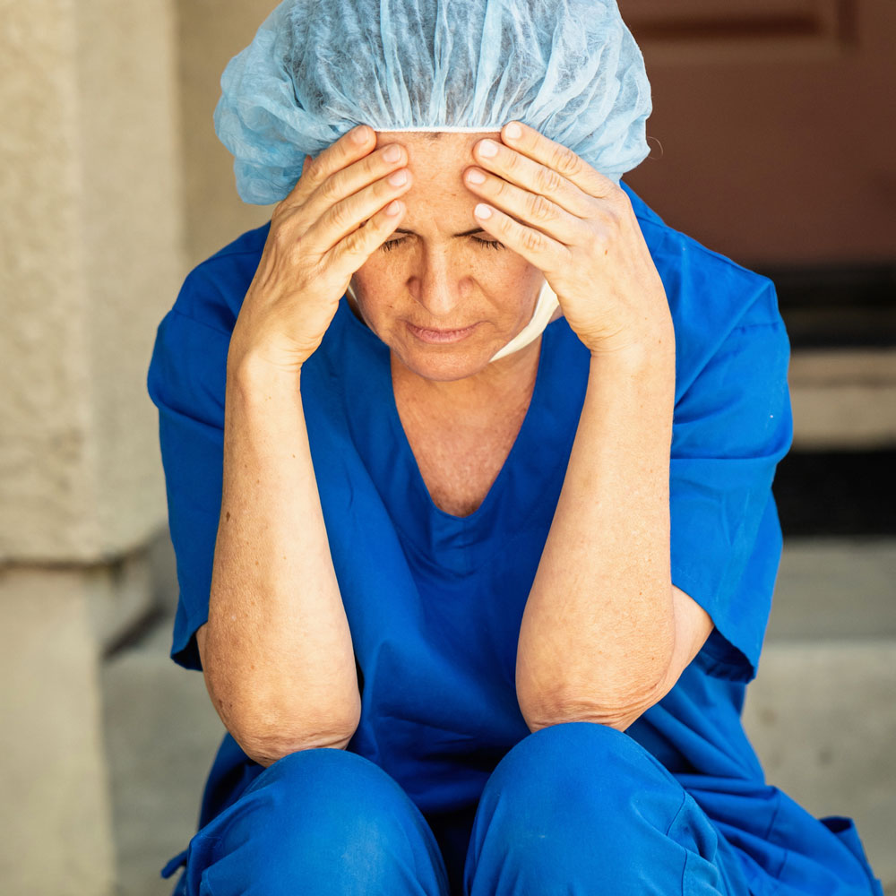 Sad and overworked nurse experiencing trauma, emphasizing the importance of Deer Hollow’s specialized addiction and mental health treatment programs for nurses struggling with PTSD and substance abuse.