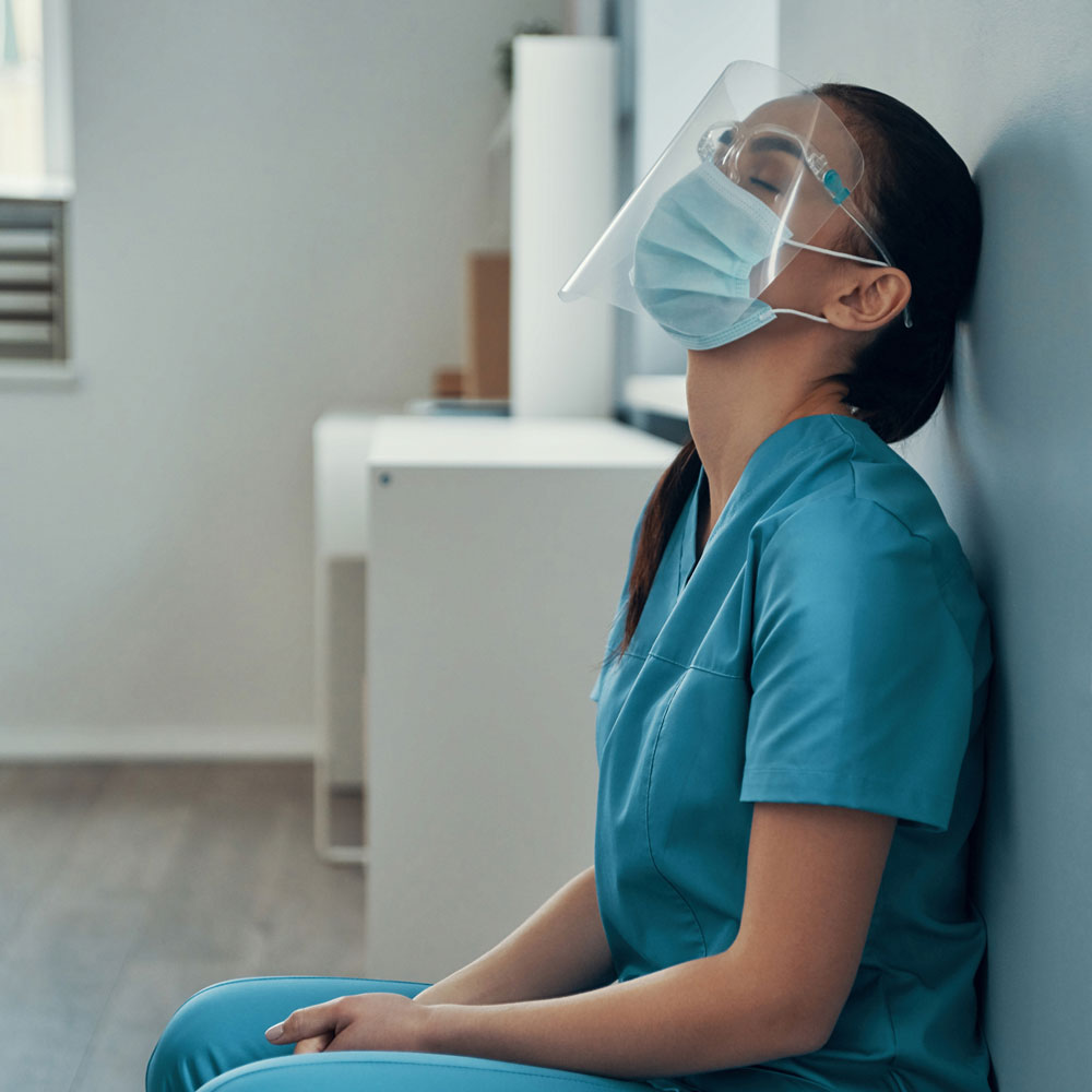 Female nurse in protective gear experiencing trauma after the death of a COVID-19 patient, emphasizing the need for Deer Hollow’s addiction treatment and mental health programs designed for nurses coping with PTSD and substance abuse.