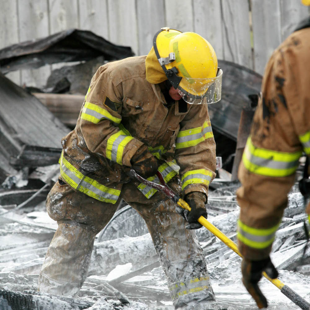 Firefighter searching through the ashes of a home fire for the remains of missing children, experiencing trauma.