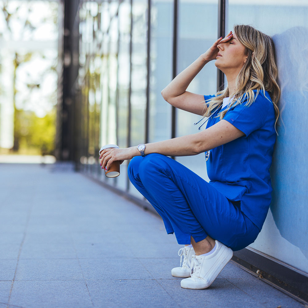 Depressed nurse feeling overwhelming guilt after the death of a child patient, emphasizing the mental health challenges faced by first responders and the specialized PTSD and addiction treatment programs offered at Deer Hollow's wellness center.