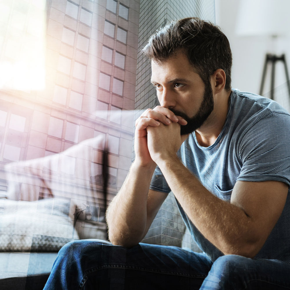 First responder sitting on couch overwhelmed by mental health challenges, considering calling off work to avoid work-related trauma, highlighting the importance of mental health treatment centers like Deer Hollow.