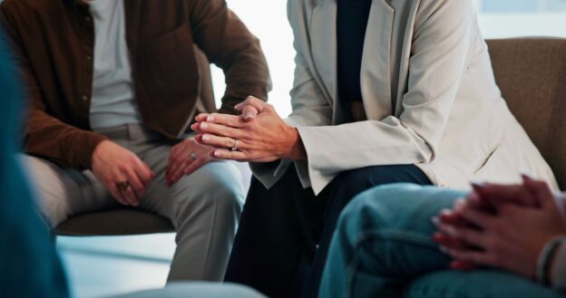 A close-up of people sitting in a circle during a support group or therapy session.